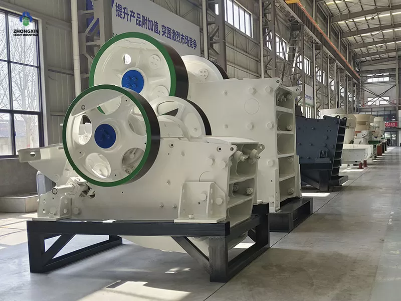 Vista lateral de la trituradora de mandíbula ZXC en la planta de fabricación, mostrando el volante de inercia y el motor