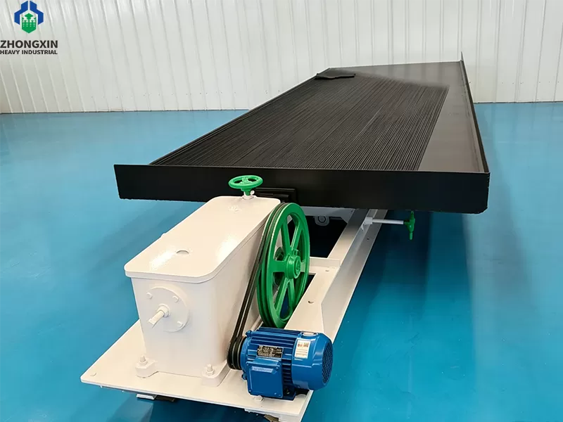Vista frontal de la mesa concentradora en la fábrica con superficie de cubierta estriada y caja de alimentación